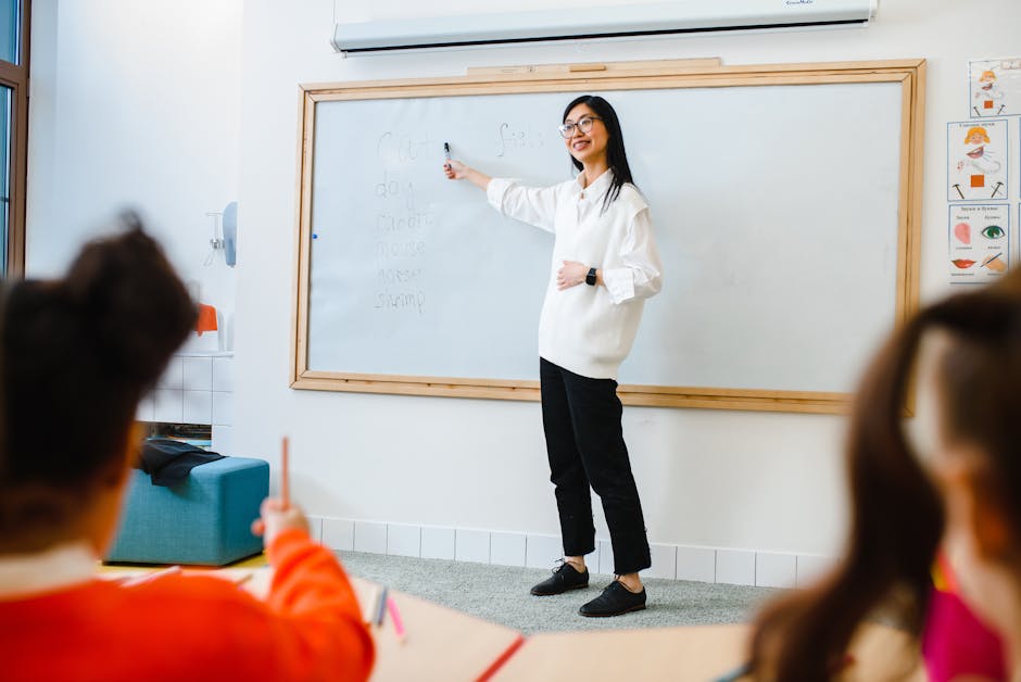 Smiling teacher instructing students in a classroom setting using a whiteboard